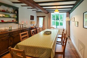 Ein Essbereich mit einem Tisch, der mit einer Tischdecke mit Punkten bedeckt ist, Holzsesseln und einer Kristallleuchtre.