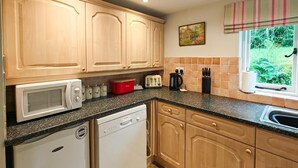 Eine Küche mit Holzausstattung, einer Mikrowelle, einem Toaster und einem Geschirrspüler.