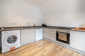 Une cuisine compacte équipée d’un lave-linge, d’un grille-pain et d’un four.