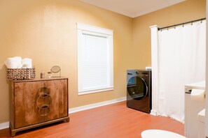 A laundry room with a washing machine, a cabinet with towels, and a window with blinds. - Cozy 2-bedroom in Cotter with walking distance to shopping, river, and food. (Cotter)