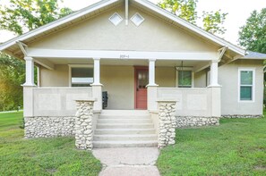 A two-story house with a front porch, stone steps, and a red door. - Cozy 2-bedroom house in Cotter, walking distance to shopping, river, and food. (Cotter)