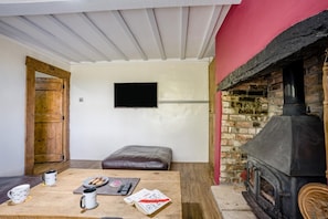 A cozy room with a fireplace, a television mounted on the wall, and a wooden door. - 3 Bed in Stoborough (oc-c44898) (Stoborough)
