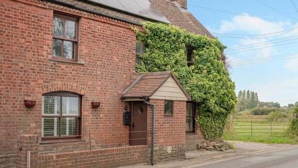 A brick house with a small attached garage, a front door, and a window with shutters. - 3 Bed in Stoborough (oc-c44898) (Stoborough)