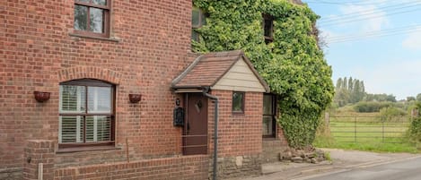 A brick house with a small porch and a window with shutters.