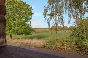 Un paysage rural avec une route asphaltée, une clôture en bois et des arbres.