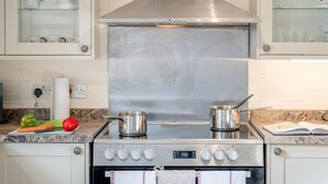A kitchen with stainless steel appliances, including a stove and oven, and a marble countertop. - 3 Bed in Stoborough (oc-c44898) (Stoborough)