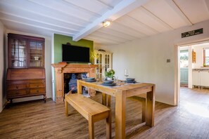 Un coin repas avec une table en bois dressée pour deux personnes, un banc et une cheminée.