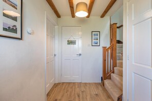 A hallway with a wooden staircase, a white door, and a framed picture on the wall. - 3 Bed in Woolacombe (oc-s45868) (Woolacombe)