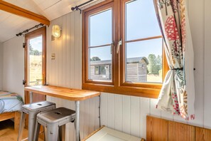 A small room with a wooden bench, a window with curtains, and a view of a building outside.