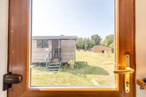 A wooden door with a view of a small cabin with a porch and steps leading to a door.