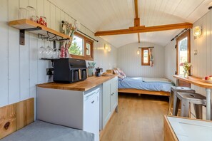 A compact kitchen with a coffee maker, a bed, and a small dining area.