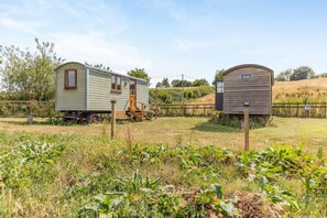 Two mobile homes in a grassy field with a wooden fence in the background.