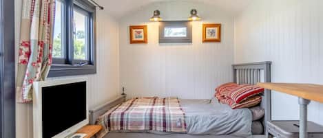 Une chambre confortable avec un lit, une télévision et une fenêtre avec des rideaux.