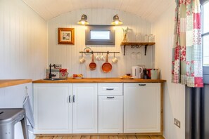 A compact kitchen with white cabinets, wooden countertops, and a hanging pot rack. - 1 Bed in Washfield (oc-s45538) (Tiverton)