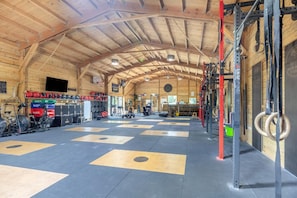 A gym with a high ceiling, weightlifting equipment, and a variety of exercise machines.