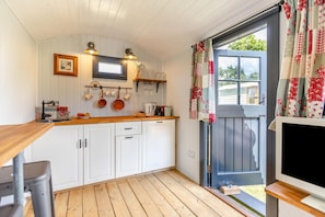 A kitchen with white cabinets, a wooden countertop, and a window with curtains.