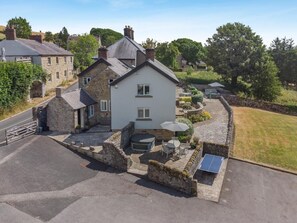 A two-story house with a stone facade, a paved driveway, and a tennis court. - 3 Bed in Wirksworth (oc-l45749) (Hopton)
