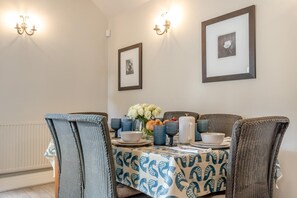 A dining area with a table set for four, featuring a patterned tablecloth, blue and white ceramic dishes, and a vase with white flowers. - 3 Bed in Wirksworth (oc-l45749) (Hopton)