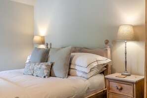 A neatly made bed with multiple pillows and a bedside table with a lamp. - 3 Bed in Wirksworth (oc-l45749) (Hopton)