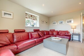 A living room with a red leather sofa, a grey coffee table, and a window with a floral blind. - 3 Bed in Wirksworth (oc-l45749) (Hopton)