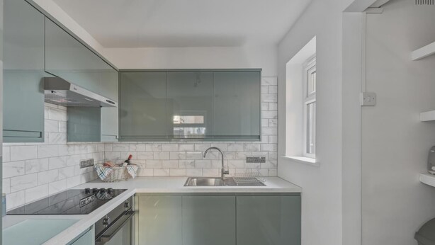 Una cocina moderna con estufa integrada, pileta y alacenas superiores.