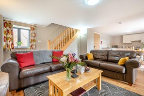 A modern living room with two leather sofas, a wooden coffee table, and a staircase leading to an upper floor. - 4 Bed in Kenilworth (oc-p45549) (Kenilworth)