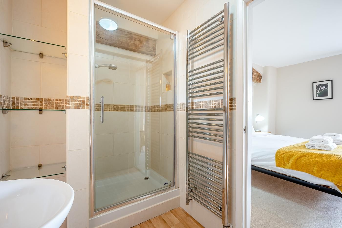 Ein Badezimmer mit Duschkabine, Waschbecken in Weiß und einer Glasablage.