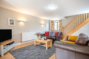 A living room with a sofa, coffee table, TV, and a staircase. - 4 Bed in Kenilworth (oc-p45549) (Kenilworth)