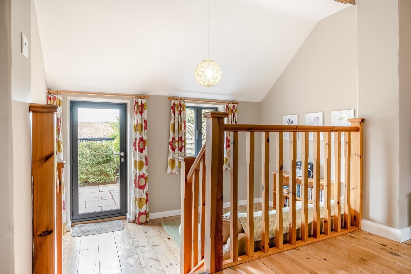 A room with a wooden staircase, a door leading outside, and a view of the garden.