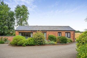 A brick house with a paved driveway and a garden with various shrubs and flowers. - 2 Bed in Kenilworth (oc-p45550) (Kenilworth)