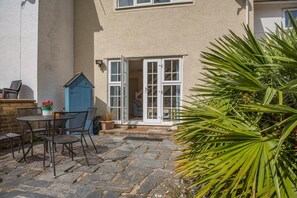 A stone patio with outdoor furniture, a blue door, and a potted plant. - 3 Bed in Borth-y-Gest (oc-t44960) (Borth-y-Gest)
