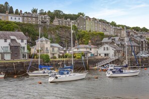 A harbor with boats docked, stone buildings, and a rocky hillside in the background. - 3 Bed in Borth-y-Gest (oc-t44960) (Borth-y-Gest)