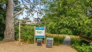 A wildlife trust signpost with a map and information board, a gravel path, and a large tree. - 3 Bed in Poole (oc-v45688) (Sandbanks)