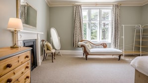 A bedroom with a vanity, a mirror, a dresser, a bed, a window with curtains, and a radiator. - 3 Bed in Poole (oc-v45688) (Sandbanks)