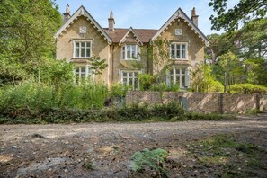 A two-story house with a brick facade, multiple windows, and a surrounding garden. - 3 Bed in Poole (oc-v45688) (Sandbanks)