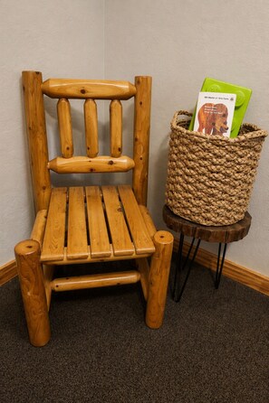 A wooden chair with a woven basket on a small wooden table beside it.
