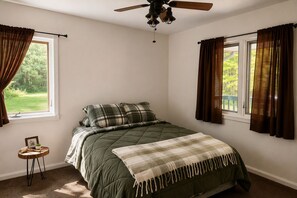 A bedroom with a bed, a ceiling fan, and windows with curtains. - Antler Lake Haus - Private Waterfront & ATV/Snowmobile Trail Access (Bigfork)