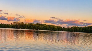 A calm lake with a dock extending into the water, surrounded by a forested shoreline.