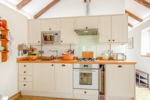 A kitchen with wooden cabinets, a gas stove, an oven, and a microwave.