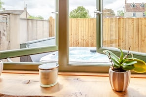 A window view of a backyard with a hot tub and a wooden fence.