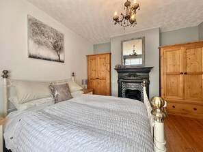 Ein Schlafzimmer mit einem großen Bett, einem Holzschrank, einem Kamin und einer Deckenleuchte.