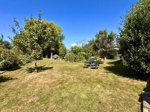 Ein Garten mit Rasenfläche, einem kleinen Gartenhaus und einem Baum.