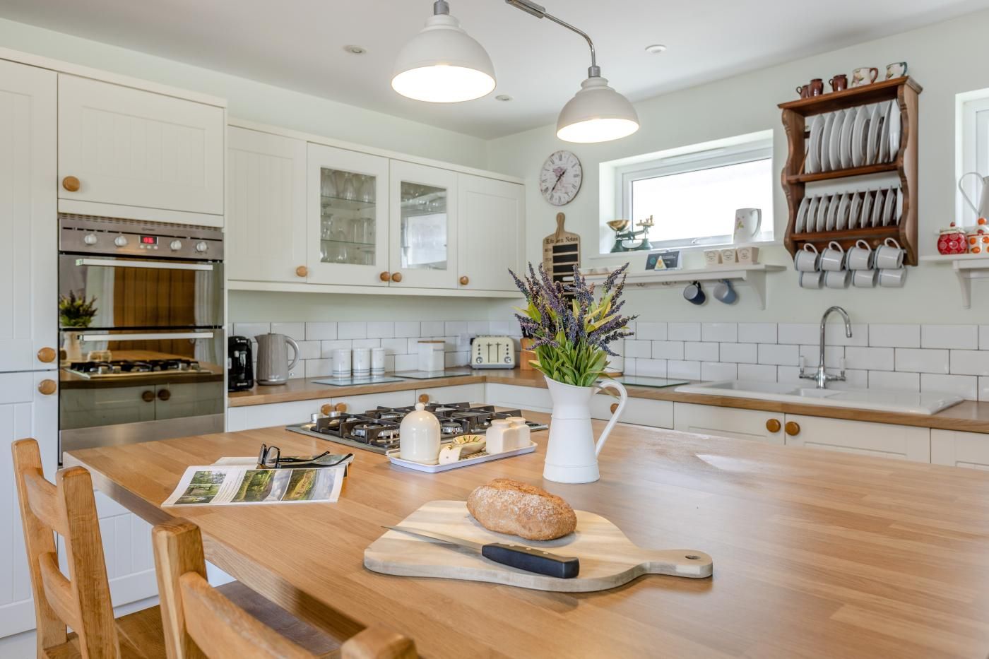 A modern kitchen with white cabinetry, a central island, a gas stove, and a wooden dining table.