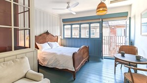 A bedroom with a bed, a chair, a table, and a balcony with a view. - 1 Bed in Swanage (oc-s45891) (Swanage)