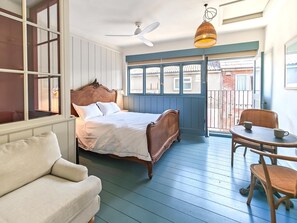 Ein Schlafzimmer mit Bett, Stuhl, Tisch und einem Balkon mit Blick.