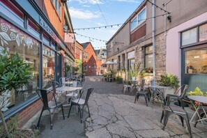 An outdoor café area with tables and chairs, surrounded by buildings with various storefronts. - 1 Bed in Swanage (oc-s45891) (Swanage)
