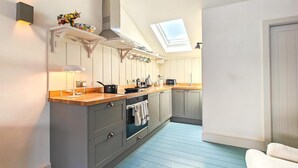 A modern kitchen with a skylight, grey cabinets, and a wooden countertop. - 1 Bed in Swanage (oc-s45891) (Swanage)
