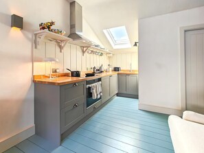Eine moderne Küche mit Oberlichter, grauen Schränken und einer Holz Arbeitsplatte.