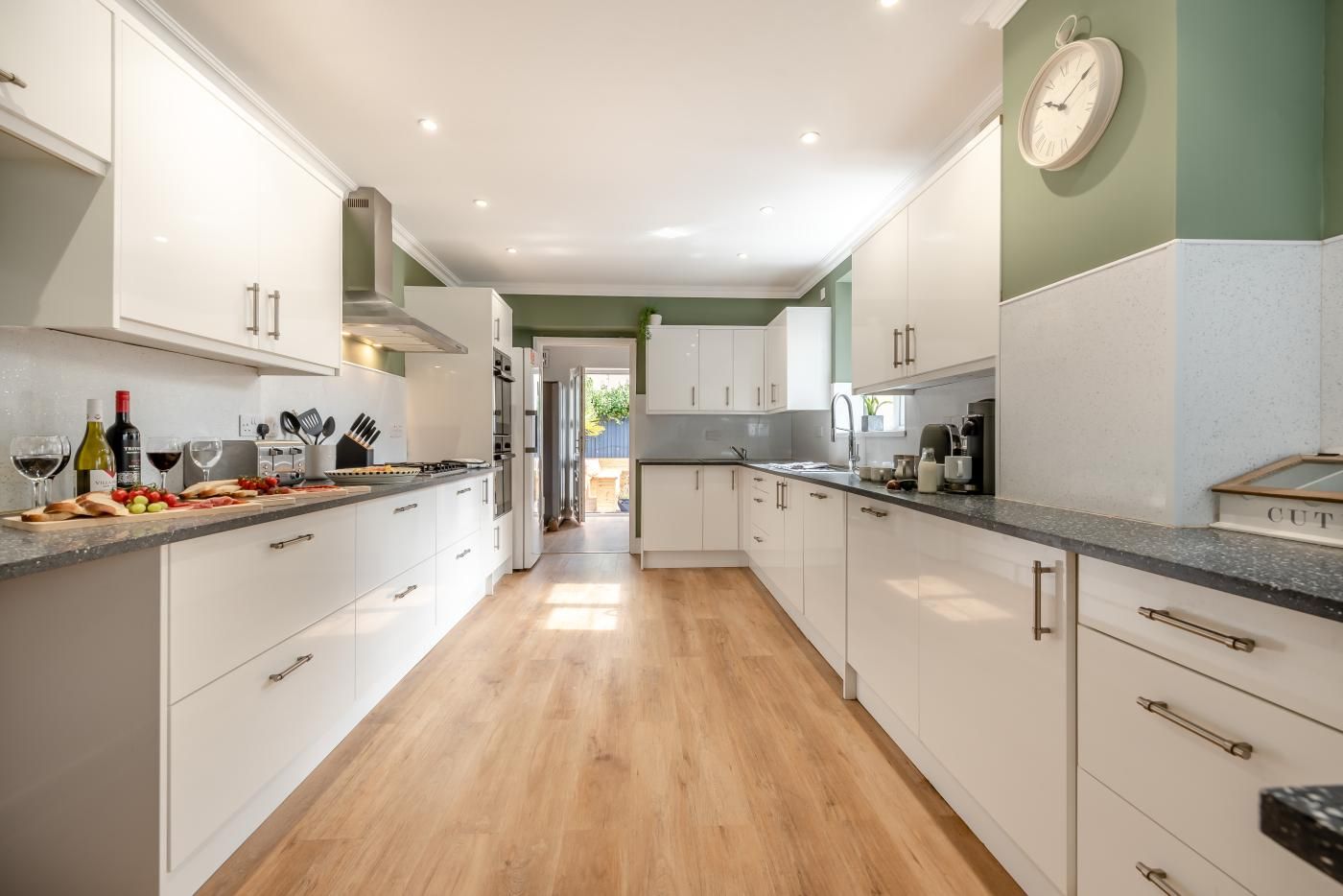 A modern kitchen with white cabinets, a wooden countertop, and a view into the dining area.