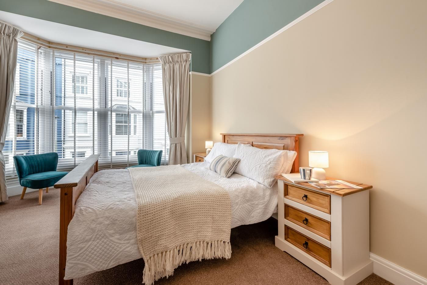A bedroom with a bed, bedside tables, a chair, and a window with curtains.